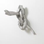 What appears to be a knot made of pliable silver metal protrudes from a white wall.